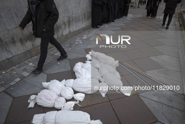 An Iranian protester walks past packages wrapped in shrouds symbolizing the bodies of people of Syria, which are placed on a sidewalk, durin...