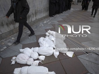 An Iranian protester walks past packages wrapped in shrouds symbolizing the bodies of people of Syria, which are placed on a sidewalk, durin...