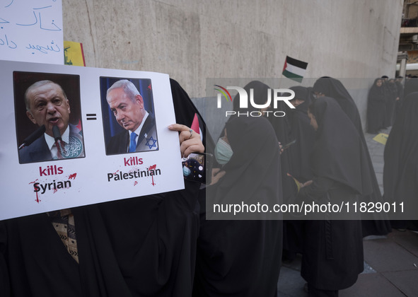 A veiled Iranian protester holds a poster featuring portraits of Turkish President Recep Tayyip Erdogan and Israeli Prime Minister Benjamin...