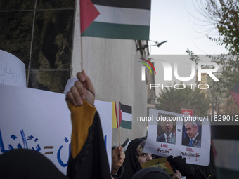 A veiled Iranian protester holds a poster featuring portraits of Turkish President Recep Tayyip Erdogan and Israeli Prime Minister Benjamin...