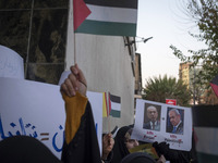 A veiled Iranian protester holds a poster featuring portraits of Turkish President Recep Tayyip Erdogan and Israeli Prime Minister Benjamin...