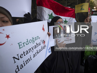 Veiled Iranian protesters hold an anti-Turkish placard and a poster featuring portraits of Turkish President Recep Tayyip Erdogan and Israel...