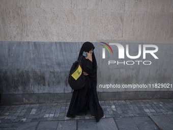 A veiled Iranian protester holds a flag of Lebanon's Hezbollah while standing on a sidewalk after a protest against Turkish President Recep...