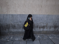 A veiled Iranian protester holds a flag of Lebanon's Hezbollah while standing on a sidewalk after a protest against Turkish President Recep...