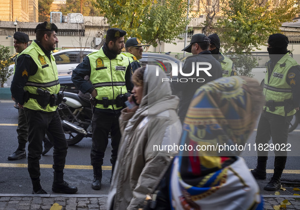 Two Iranian women walk past policemen standing guard during a protest against Turkish President Recep Tayyip Erdogan and his diplomacy regar...