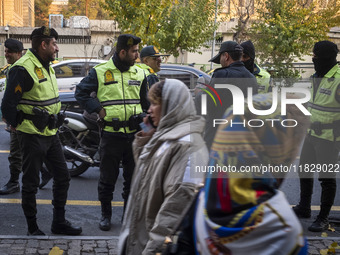 Two Iranian women walk past policemen standing guard during a protest against Turkish President Recep Tayyip Erdogan and his diplomacy regar...