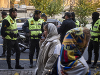 Two Iranian women walk past policemen standing guard during a protest against Turkish President Recep Tayyip Erdogan and his diplomacy regar...