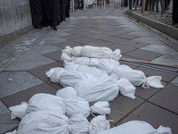 Veiled Iranian policewomen stand near packages wrapped in shrouds symbolizing the bodies of people of Syria, which are placed on a sidewalk,...