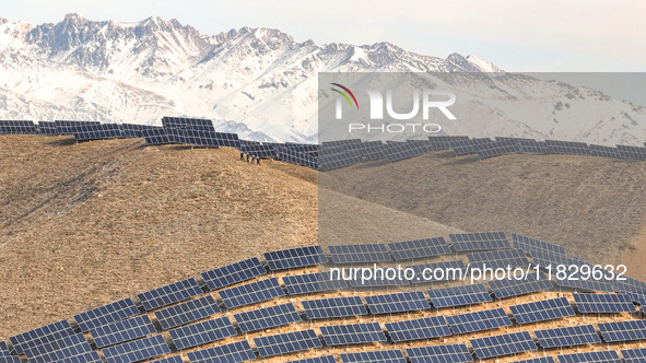 Workers of Huaneng Yili Xexin Photovoltaic Power Plant inspect equipment on a barren slope in Yili, Xinjiang province, China, on November 30...