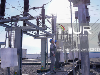 Workers of Huaneng Yili Xexin Photovoltaic Power Plant inspect equipment on a barren slope in Yili, Xinjiang province, China, on November 30...