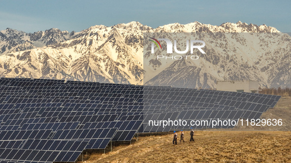 Workers of Huaneng Yili Xexin Photovoltaic Power Plant inspect equipment on a barren slope in Yili, Xinjiang province, China, on November 30...