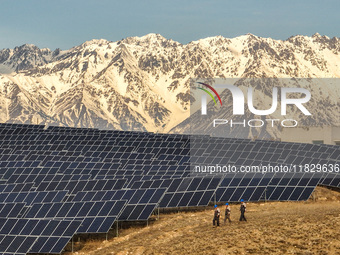 Workers of Huaneng Yili Xexin Photovoltaic Power Plant inspect equipment on a barren slope in Yili, Xinjiang province, China, on November 30...