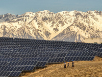 Workers of Huaneng Yili Xexin Photovoltaic Power Plant inspect equipment on a barren slope in Yili, Xinjiang province, China, on November 30...