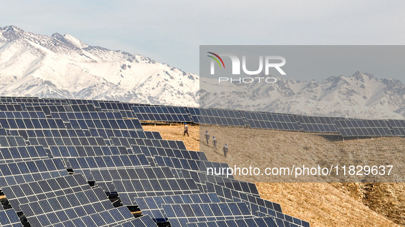 Workers of Huaneng Yili Xexin Photovoltaic Power Plant inspect equipment on a barren slope in Yili, Xinjiang province, China, on November 30...