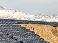 Workers of Huaneng Yili Xexin Photovoltaic Power Plant inspect equipment on a barren slope in Yili, Xinjiang province, China, on November 30...