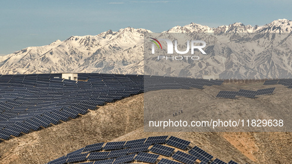 Workers of Huaneng Yili Xexin Photovoltaic Power Plant inspect equipment on a barren slope in Yili, Xinjiang province, China, on November 30...