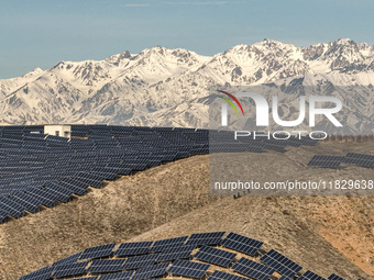 Workers of Huaneng Yili Xexin Photovoltaic Power Plant inspect equipment on a barren slope in Yili, Xinjiang province, China, on November 30...