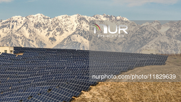 Workers of Huaneng Yili Xexin Photovoltaic Power Plant inspect equipment on a barren slope in Yili, Xinjiang province, China, on November 30...