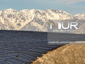 Workers of Huaneng Yili Xexin Photovoltaic Power Plant inspect equipment on a barren slope in Yili, Xinjiang province, China, on November 30...