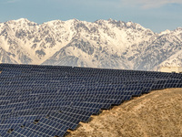 Workers of Huaneng Yili Xexin Photovoltaic Power Plant inspect equipment on a barren slope in Yili, Xinjiang province, China, on November 30...