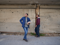 Two men walk past shops hit by shrapnel and bullets in the Bustan al-Qasr neighborhood in Aleppo, Syria, on December 1, 2024. (