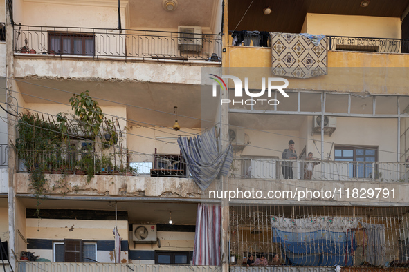 Residents stand on the balcony of their home in the Bustan Al Qasr neighborhood in Aleppo, on December 1, 2024 