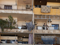 Residents stand on the balcony of their home in the Bustan Al Qasr neighborhood in Aleppo, on December 1, 2024 (