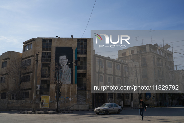 A man walks past a government building with a picture of Syrian President Bashar al-Assad in Aleppo, Syria, on December 1, 2024. 