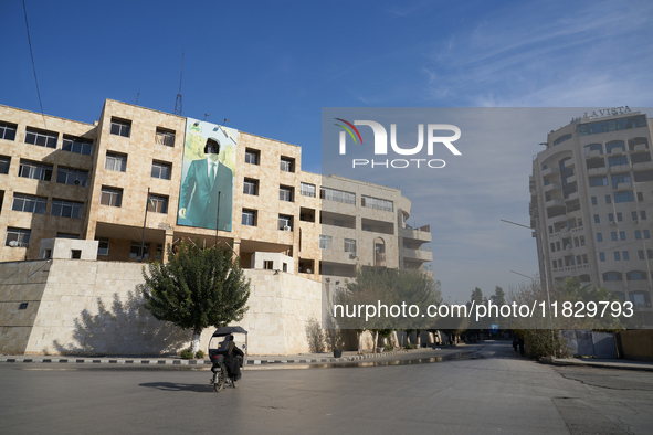 A man walks past a government building with a defaced picture of Syrian President Bashar al-Assad in Aleppo, Syria, on December 1, 2024. 