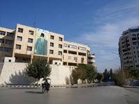 A man walks past a government building with a defaced picture of Syrian President Bashar al-Assad in Aleppo, Syria, on December 1, 2024. (