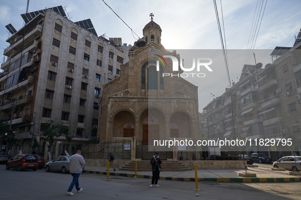 Residents walk near a church in Aleppo, Syria, on December 1, 2024, after the armed opposition takes control of the city. 