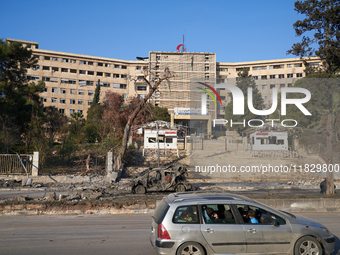 A Syrian family drives past the university hospital, which the Syrian regime targets with airstrikes after opposition forces take control of...