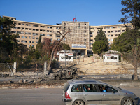 A Syrian family drives past the university hospital, which the Syrian regime targets with airstrikes after opposition forces take control of...