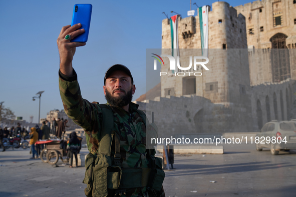 A Syrian opposition fighter takes a selfie in front of the ancient citadel of Aleppo after taking control of the city in Aleppo, Syria, on D...