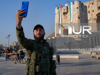 A Syrian opposition fighter takes a selfie in front of the ancient citadel of Aleppo after taking control of the city in Aleppo, Syria, on D...