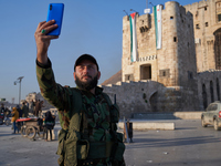 A Syrian opposition fighter takes a selfie in front of the ancient citadel of Aleppo after taking control of the city in Aleppo, Syria, on D...