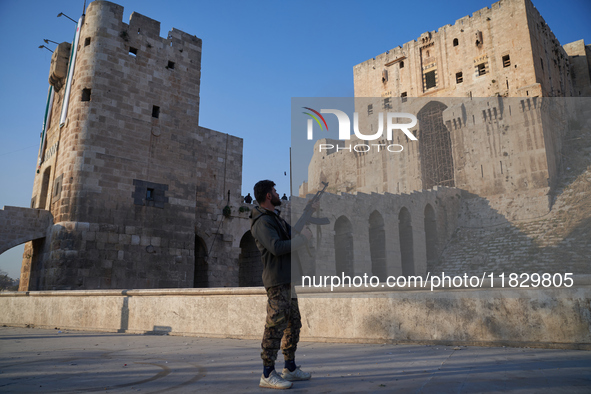 A Syrian armed opposition fighter fires a gun into the air after taking control of the city in Syria on December 1, 2024. 