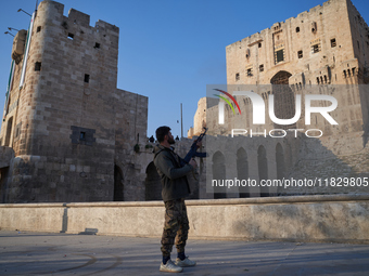 A Syrian armed opposition fighter fires a gun into the air after taking control of the city in Syria on December 1, 2024. (