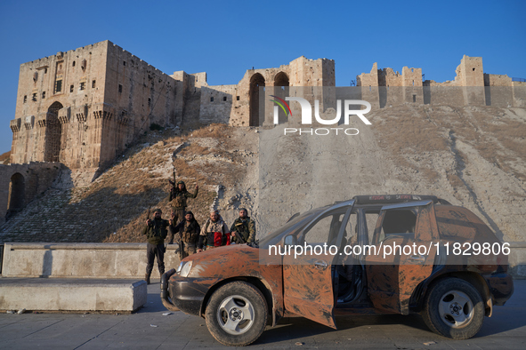 Syrian opposition fighters pose for a photo in front of the ancient citadel of Aleppo after taking control of the city in Aleppo, Syria, on...