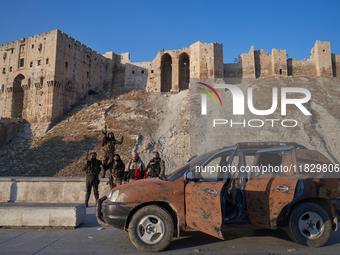 Syrian opposition fighters pose for a photo in front of the ancient citadel of Aleppo after taking control of the city in Aleppo, Syria, on...