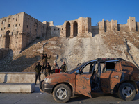 Syrian opposition fighters pose for a photo in front of the ancient citadel of Aleppo after taking control of the city in Aleppo, Syria, on...