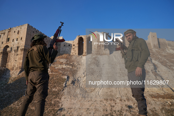 Syrian opposition fighters pose for a photo in front of the ancient citadel of Aleppo after taking control of the city in Aleppo, Syria, on...