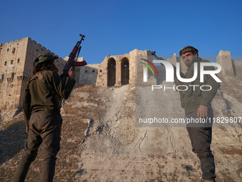 Syrian opposition fighters pose for a photo in front of the ancient citadel of Aleppo after taking control of the city in Aleppo, Syria, on...