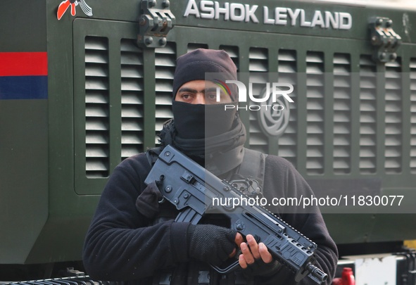 An Indian security personnel stands guard along a road during an encounter on the outskirts of Srinagar, Jammu and Kashmir, on December 3, 2...