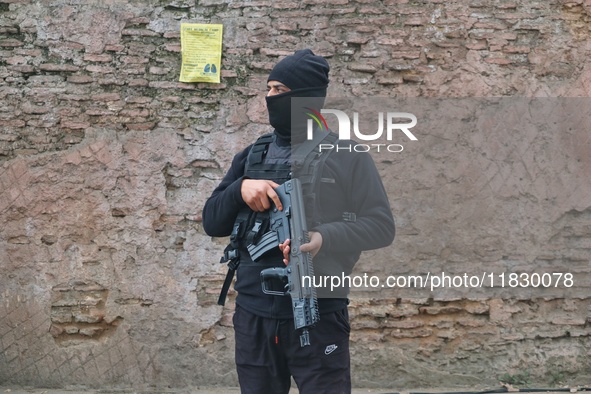 An Indian security personnel stands guard along a road during an encounter on the outskirts of Srinagar, Jammu and Kashmir, on December 3, 2...