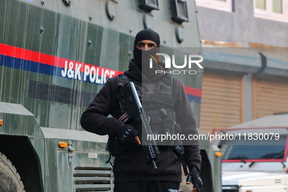 An Indian security personnel stands guard along a road during an encounter on the outskirts of Srinagar, Jammu and Kashmir, on December 3, 2...