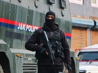 An Indian security personnel stands guard along a road during an encounter on the outskirts of Srinagar, Jammu and Kashmir, on December 3, 2...