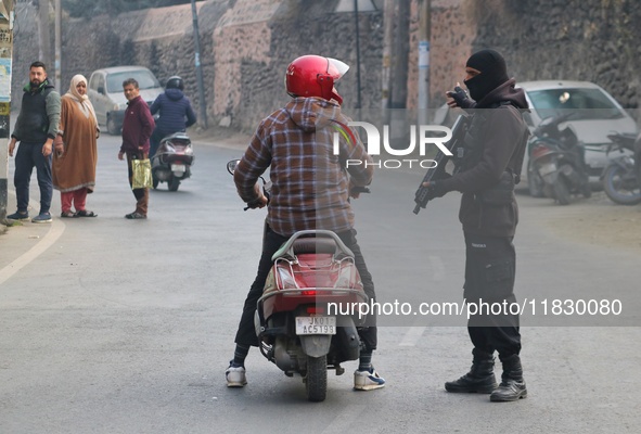 An Indian security personnel stops a motorcyclist during an encounter on the outskirts of Srinagar, Jammu and Kashmir, on December 3, 2024....