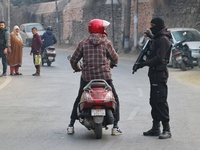 An Indian security personnel stops a motorcyclist during an encounter on the outskirts of Srinagar, Jammu and Kashmir, on December 3, 2024....