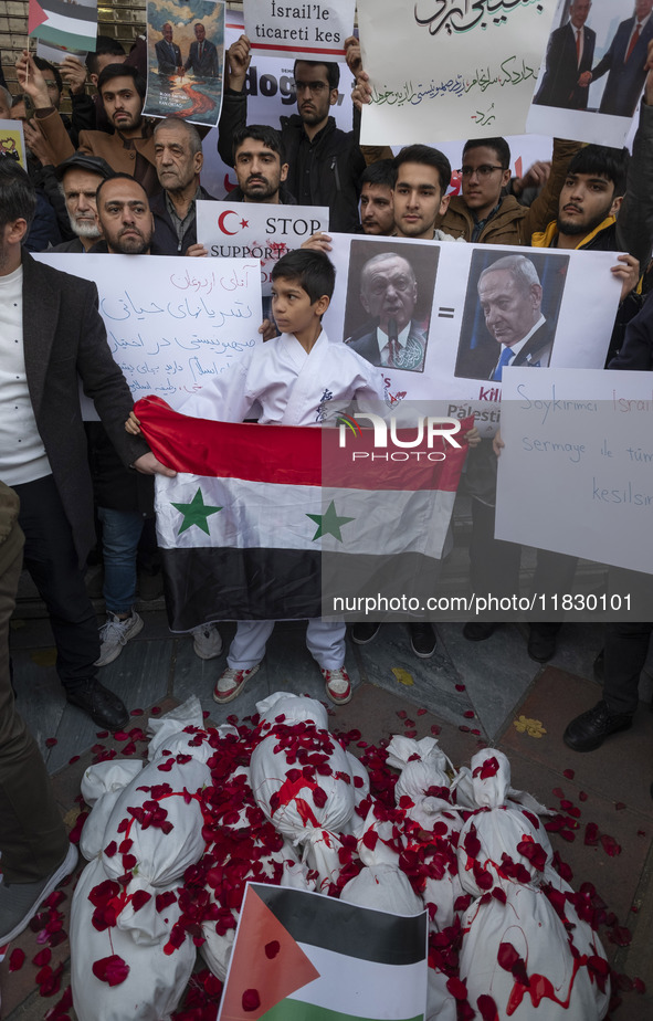 A young Iranian protester holds a Syrian flag while standing behind packages wrapped in shrouds symbolizing the bodies of people of Syria du...